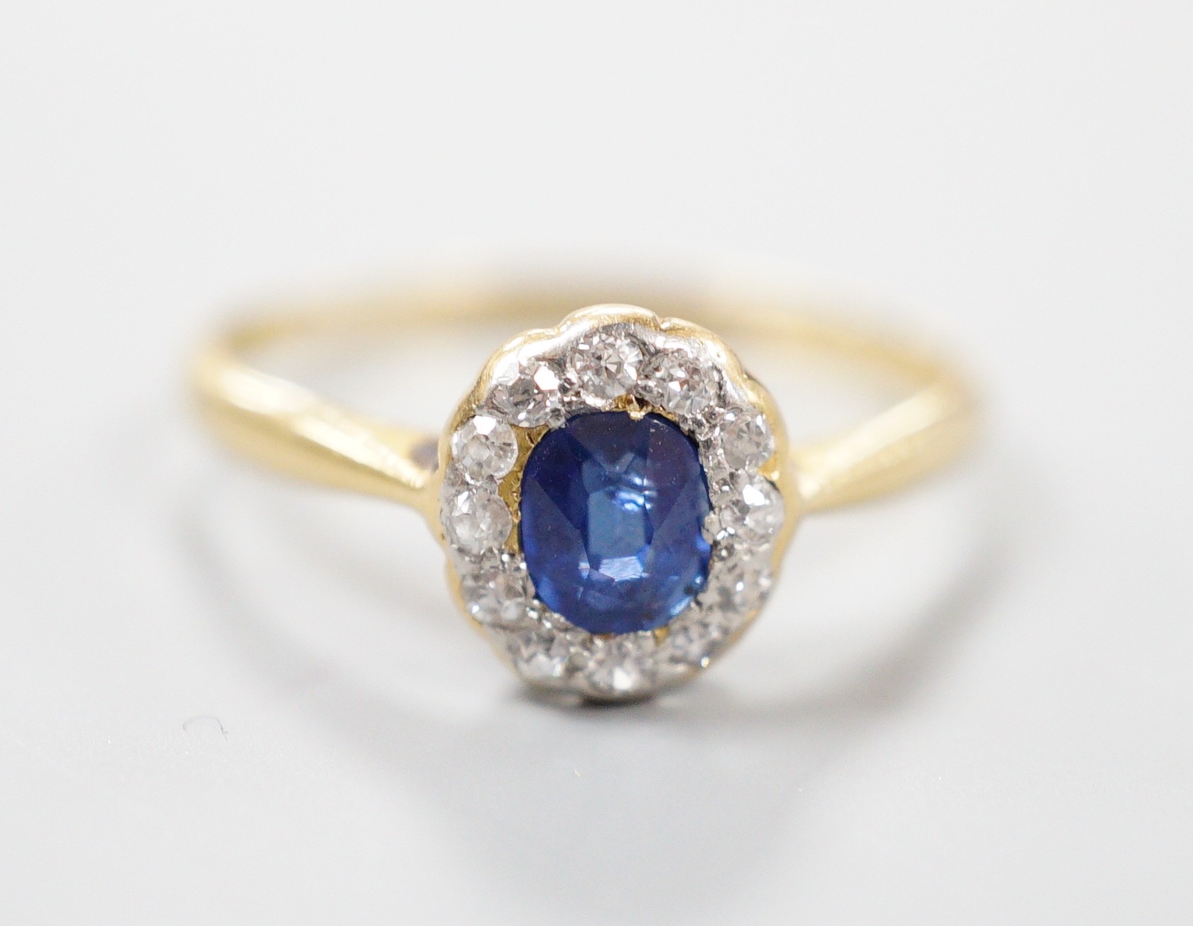 An 18ct, sapphire and diamond set oval cluster ring, size M, gross weight 1.7 grams.